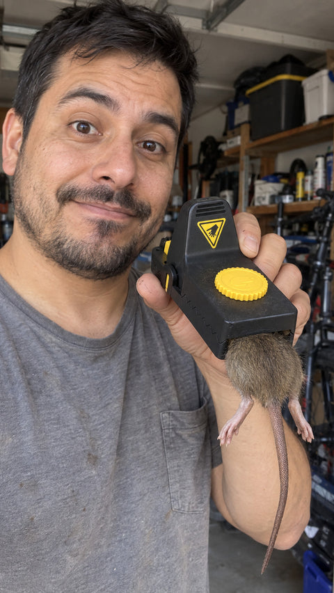 Man in his garage holding a Jovia trap with a caught rat