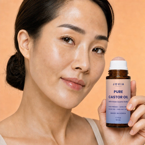 Woman with bright, rested under-eyes holding Jovia castor oil